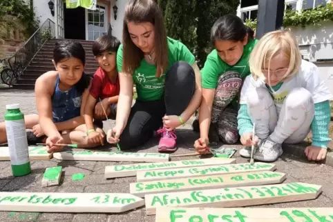 Hasna, Sobhi, Paula, Solin und Martha bauen einen Wegweiser auf dem die Entfernung zum jeweiligen Heimatort in KM angegeben ist.