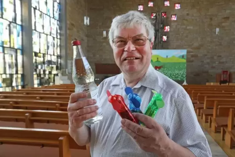 Pfarrer Friedhelm Hans reicht Kirchenbesuchern künftig Mineralwasser und Handventilatoren. Foto: van