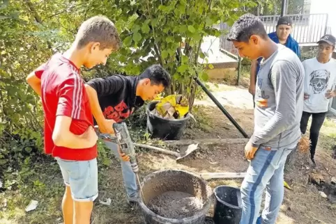Schüler rühren Beton im Kübel an.