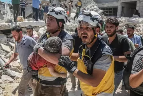 Nach Luftangriffen tragen Weißhelme des syrischen Zivilschutzes ein verletztes Kind aus den Trümmern eines zerstörten Gebäudes i