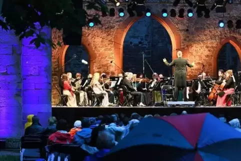 Aufgespannte Regenschirme vor der Bühne: Die Musikreise durch 100 Jahre Filmgeschichte verlief trotzdem hervorragend.  Foto: Fra