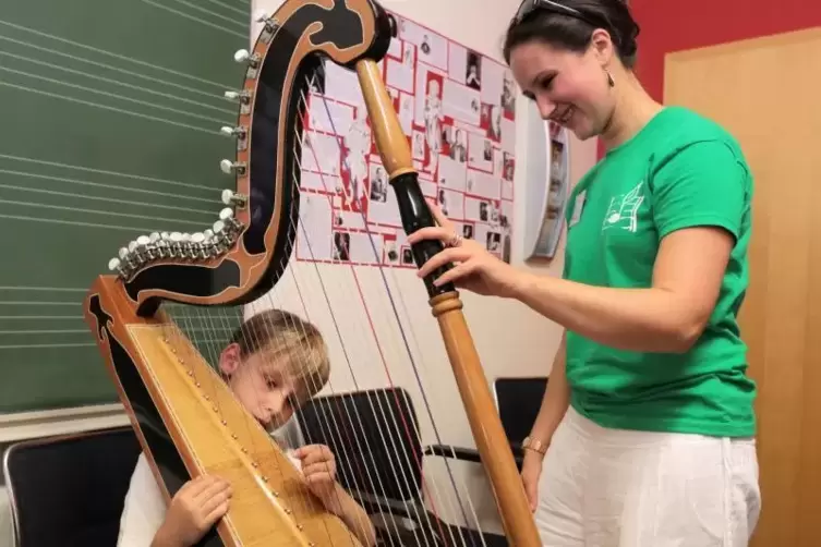 Lars probiert in der Musikschule Leiningerland das Harfespielen. Lehrerin Lena Maria Kosack hält sie.  Foto: Benndorf