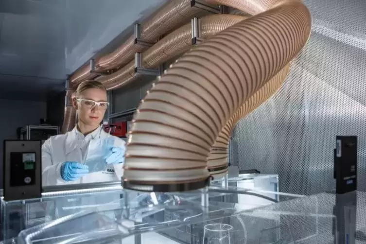 Eine BASF-Chemikerin vor einer Abzugseinrichtung in der Forschung schaut sich eine Batteriezelle an, die Kathodenmaterial des Ch