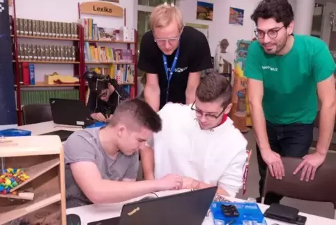 Die Schüler Dennis Schneidereit und Tim Völker (vorne von links) beim Programmieren eines Speichers sowie die Turingbus-Mitarbei