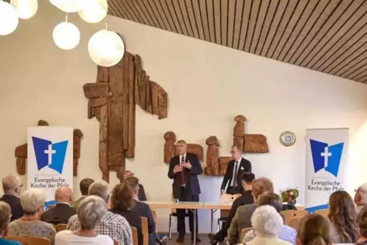 Kirchenpräsident Christian Schad (Mitte) steht im Haus der Kirche Rede den Zuhörern und Antwort.