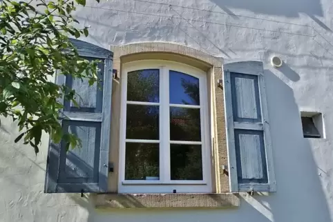 Zum hellen Anstrich des Hauses passt das dezente Blau der Klappläden.