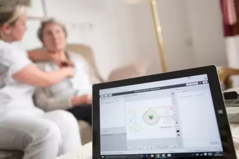 Anwendung von Telemedizin im Seniorenheim: Eine Pflegerin legt einer Bewohnerin ein EKG-Gerät an, das die Daten zum Arzt überträ