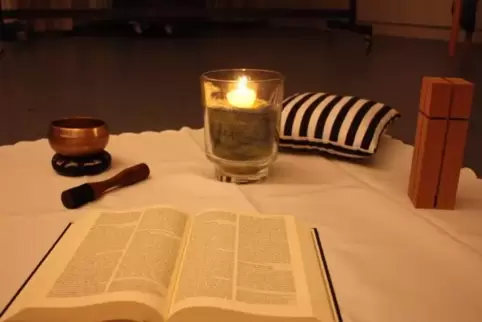 Der Raum ist abgedunkelt. In der Mitte: Klangschale, Kerze, Kreuz und Bibel – als Hinweis auf das übergeordnete Ziel des Abends.