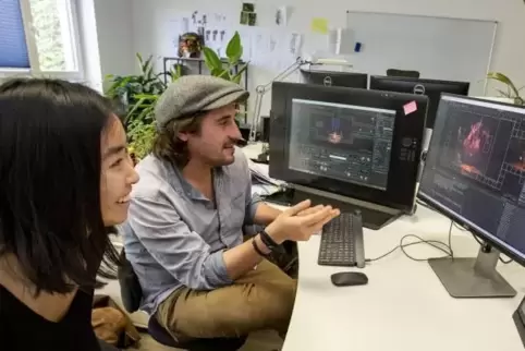Die neue Social-Media-Beauftragte von Grimbart Tales, Aika Futakuchi, und Artur Becker schauen sich gemeinsam eine der Zwischens