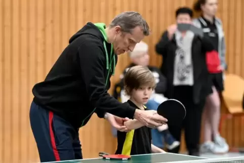 Der Weltmeister zeigt die richtige Schlägerhaltung: Jörg Roßkopf mit dem neunjährigen Ben Luca Heiser.