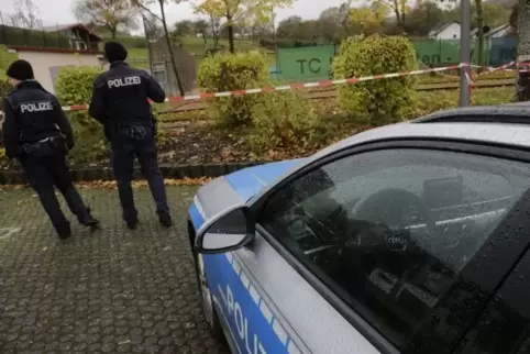 Polizisten vor dem abgesperrten Tennisplatz-Gelände in Hoppstädten, in dessen Umgebung der Mann mit der Axt gesehen worden war.