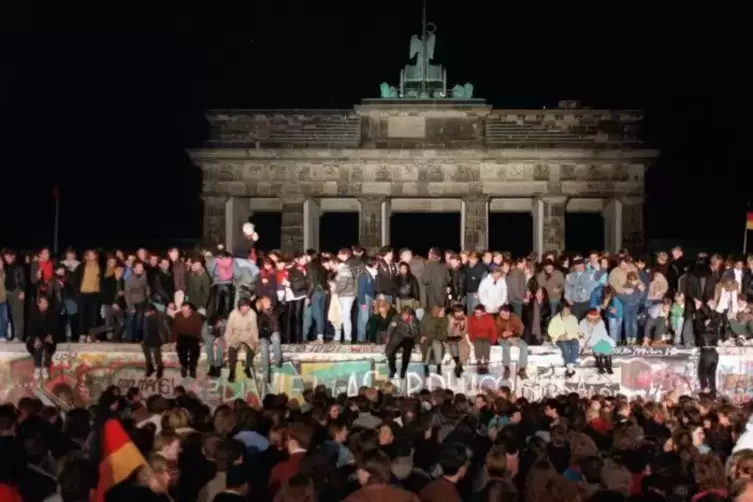 November 1989: Jubelnde Menschen auf der Berliner Mauer.