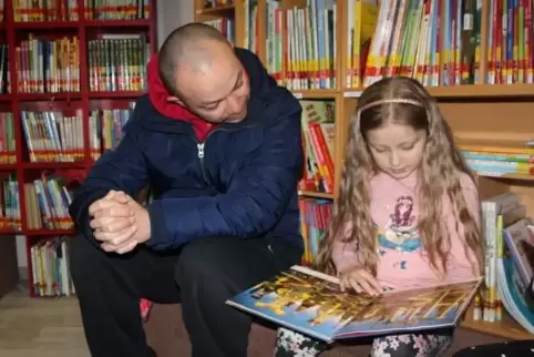 Melody zeigt ihrem Vater Tarik Isik das Buch, das sie gerade aus dem Regal gezogen hat. Er hat seine Tochter in der Ramsteiner B