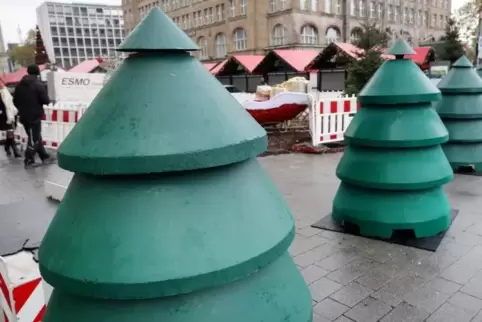 Als Weihnachtsbäume gestaltete Beton-Durchfahrtssperren stehen vor dem Eingangsbereich eines Weihnachtsmarktes in Essen.