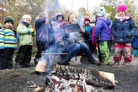 Vorlesen in der Waldgruppe der Flohkiste: Die Kinder scharen sich um Jana Schreiber und das Lagerfeuer.