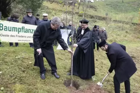 Nach der Kranzniederlegung am Gefallenendenkmal pflanzen Ortsbürgermeister Eckhard Vogel, Pfarrer Frank Wiehle und Imam Musawar 