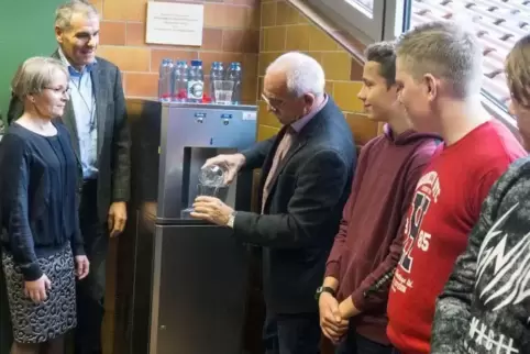 Bürgermeister Werner Kölsch (Mitte) überreicht das erste Glas aus dem neuen Wasserspender an Schulleiterin Arlett Hübsch und den