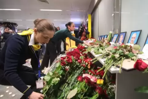 Mitarbeiter der Fluggesellschaft Ukraine International Airlines (UIA) arrangieren Blumen vor Portraits der Besatzungsmitglieder 